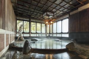 een zwembad met water in een kamer met een standbeeld bij Futsukaichi Hot Spring - Daimaru Besso in Chikushino