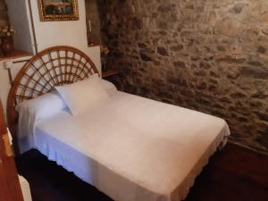 a white bed in a room with a brick wall at Ca'Pelayo in Campomanes