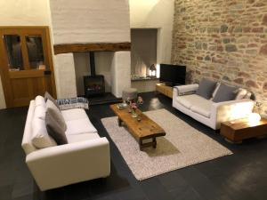 a living room with two white couches and a fireplace at Dan y Graig Barn, Carmarthen in Carmarthen
