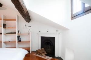 a white room with a fireplace and a bed at La mansarda sui Navigli in Milan