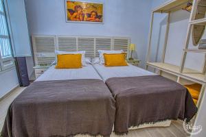 Un dormitorio con una cama grande con almohadas amarillas. en CASA ARCO DEL CAÑÓN - Casita con Encanto, en Medina Sidonia