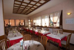 een restaurant met tafels en stoelen met rode en witte tafelkleden bij Albergo Ristorante Galli in Pievepelago