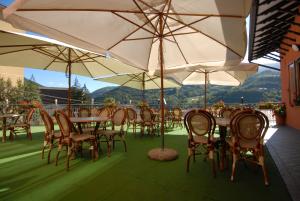 een groep tafels en stoelen met parasols bij Albergo Ristorante Galli in Pievepelago