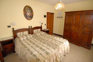 een slaapkamer met een bed en een houten dressoir bij Albergo Ristorante Galli in Pievepelago
