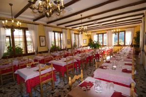 een eetkamer met tafels met rood en wit linnengoed bij Albergo Ristorante Galli in Pievepelago
