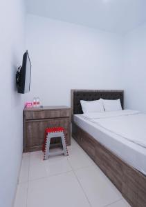 ein Schlafzimmer mit einem Bett und einem kleinen Stuhl in der Unterkunft ratana cengkareng syariah in Jakarta