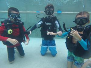 a group of children wearing diving equipment in an aquarium at Bamboo Cottage Langkawi in Pantai Cenang