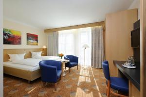a hotel room with a bed and a table and chairs at Johannesbad Hotel Füssinger Hof in Bad Füssing