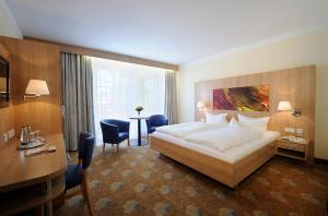 a hotel room with a large bed and a desk at Johannesbad Hotel Füssinger Hof in Bad Füssing +24 photos