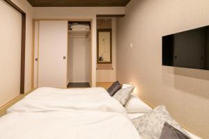 een slaapkamer met een wit bed en een flatscreen-tv bij CASA GRApP Nishikujyo in Osaka +68 foto's