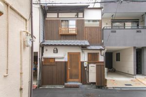 een huis met houten deuren en een balkon bij CASA GRApP Nishikujyo in Osaka
