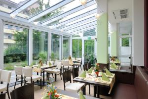Johannesbad Hotel Phönix في باد فسينغ: مطعم بطاولات وكراسي في غرفة بها نوافذ