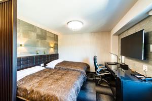 伊万里市にあるHOTEL WINのベッド、デスク、テレビが備わるホテルルームです。