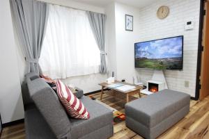 a living room with a couch and a tv at Wayado Sapporo Ciao in Sapporo