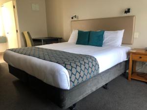 a bedroom with a large bed with blue and white pillows at 555 Motel Dunedin in Dunedin