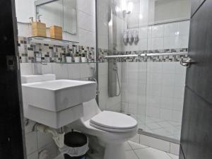 Baño blanco con lavabo y aseo en SERENADE Lodging Rooms, en Panamá