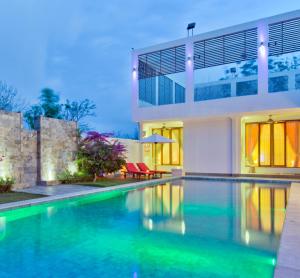 a swimming pool in front of a house at Sunset Villa in Jimbaran