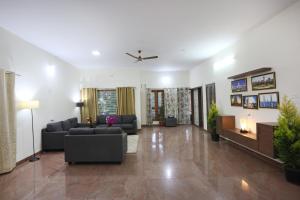 LikeMyHome Homestay Mysore في ميسور: غرفة معيشة مع كنبتين وتلفزيون