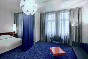 a hotel room with a bed and a chair and a chandelier at Hotel König von Ungarn in Vienna