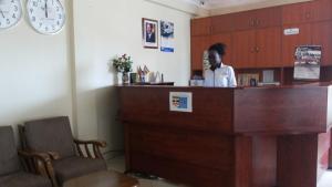 a woman standing at a reception desk in a room at Hotel Good News in Lira