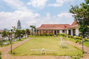 un patio con parque infantil frente a una casa en RedDoorz @ Hotel Damanaka Pangalengan en Pengalongan