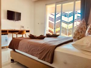 a bedroom with a bed with a large window at Radha Homestay in Sanur