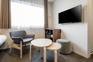 a hotel room with a chair and a table and a tv at M's Hotel Kyoto Station Kizuya in Kyoto
