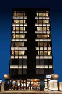 un edificio alto y negro con muchas ventanas por la noche en Place Hotel Ascot en Kumamoto