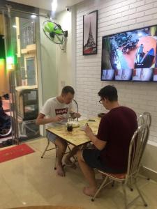 dos hombres sentados en una mesa en un restaurante en Minh Đức hotel, en Cat Ba