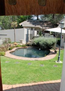 a small swimming pool in a yard with an umbrella at Buller's Rest Guest Lodge in Ladysmith