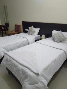 two white beds sitting next to each other in a room at Hotel the Ideal in Kushinagar