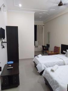 um quarto de hotel com duas camas e uma sala de estar em Hotel the Ideal em Kushinagar