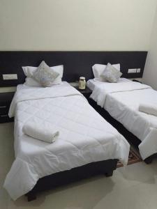 two beds in a room with white sheets and pillows at Hotel the Ideal in Kushinagar