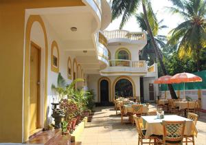 a restaurant with tables and chairs in front of a building at Time & Leisure Hotels in Candolim