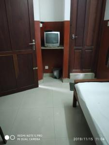 1 dormitorio con 1 cama y TV en una habitación en UNNIKRISHNA LODGE, en Kochi