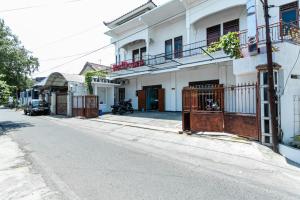 une rue vide devant un bâtiment blanc dans l'établissement RedDoorz near Puro Mangkunegaran, à Solo