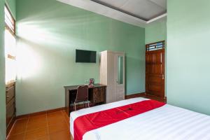 - une chambre avec un lit et une télévision murale dans l'établissement RedDoorz near Puro Mangkunegaran, à Solo