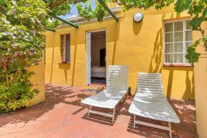 deux chaises assises devant une maison jaune dans l'établissement Fernando's the Grange, à Port Elizabeth