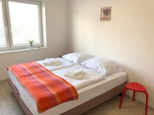 a bed with two towels and a red stool in a room at Apartmány LETO in Frýdek-Místek
