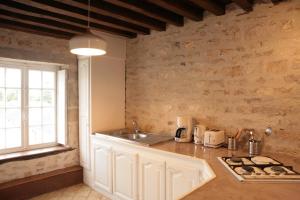 eine Küche mit einer Arbeitsfläche mit Spüle und einem Fenster in der Unterkunft Gîte Design in Arceau