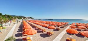 a row of orange umbrellas and chairs on a beach at Green Garden Village in Sirolo