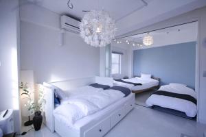a white bedroom with two beds and a chandelier at STAY ARI Arakicho in Tokyo