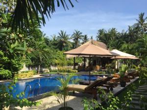 un resort con piscina con sedie e ombrellone di Mutiara Bali a Candidasa