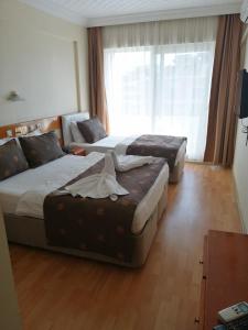um quarto de hotel com duas camas e um sofá em Grand Didyma Hotel em Didim