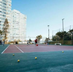 a tennis court with tennis balls on the court at 6 personas FRENTE AL MAR- Complejo LINCOLN CENTER- Torre WASHINGTON in Punta del Este