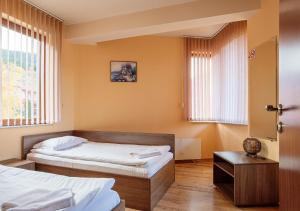 1 dormitorio con 2 camas, mesa y ventanas en Rodopi Houses en Chepelare