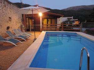 a large swimming pool with chairs and an umbrella at Casa Rural Casona de Jerte in Jerte