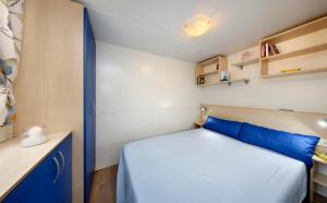 Un pequeño dormitorio con una cama azul y armarios en Albatross Mobile Homes on Camping San Francesco, en Duna Verde