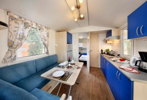 een woonkamer met een blauwe bank en een tafel bij Albatross Mobile Homes on Camping San Francesco in Duna Verde