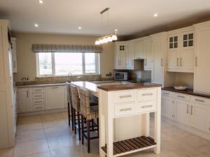a kitchen with white cabinets and a island with bar stools at The Willows at Mullans Bay in Kesh